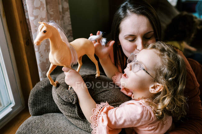 Little girl with glasses looking outside with her mother by a window — Stock Photo