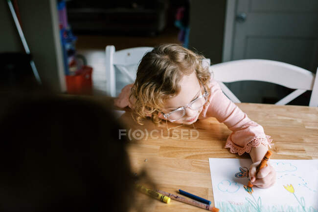 Маленькая девочка в очках, за столом со своей семьей — стоковое фото