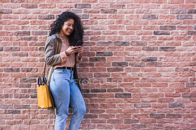Una joven afroamericana feliz hablando con un celular en la ciudad - foto de stock