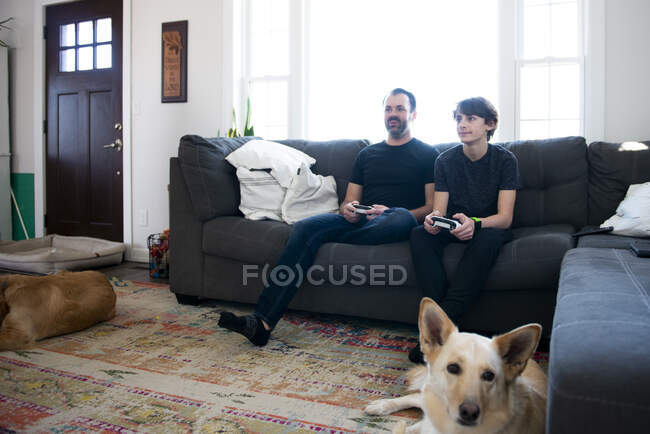 Pai e filho jogando videogames juntos no sofá. — Fotografia de Stock