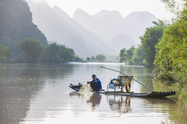 Pescador em jangada tradicional no rio Yulong perto de Yangshuo — Fotografia de Stock