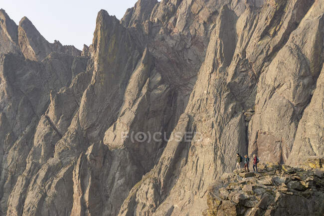 Male and female friends looking at view while standing on rocks against cliff — Stock Photo