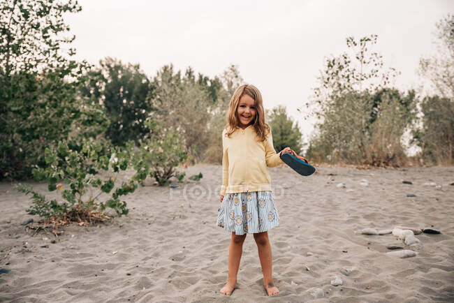 Young girl smiling in the sand on a beach by the Yellowstone River — Stock Photo