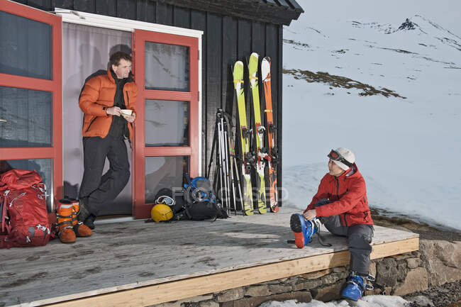 Pareja preparándose para el esquí de travesía en la casa de esquí en Islandia - foto de stock