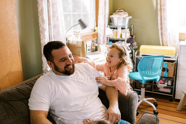 Padre e hija riendo juntos en la sala de estar - foto de stock