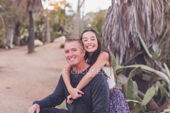 Pre-teen daughter of mixed race hugging her Caucasian father. — Stock Photo