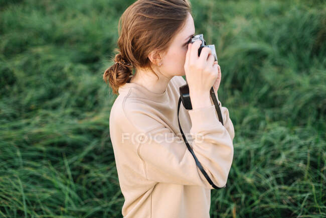 Jolie femme tenant une caméra dans un champ — Photo de stock