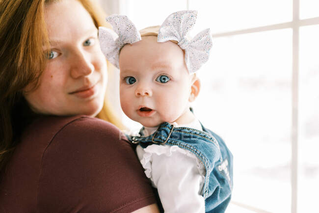 Una niña en brazos de su madre mirando con sorpresa - foto de stock