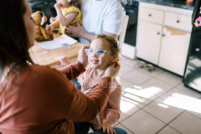 Ein kleines Vorschulmädchen mit Brille lächelt ihre Mutter liebevoll an — Stockfoto