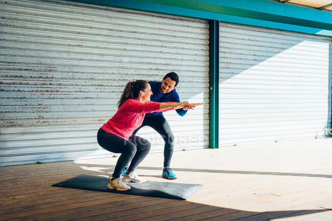 Особистий тренер навчає 49-річну жінку, як правильно виконувати вправи . — стокове фото