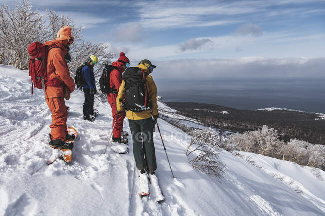 Personas en ropa de abrigo con tablas de snowboard con vistas al paisaje contra el cielo durante las vacaciones - foto de stock
