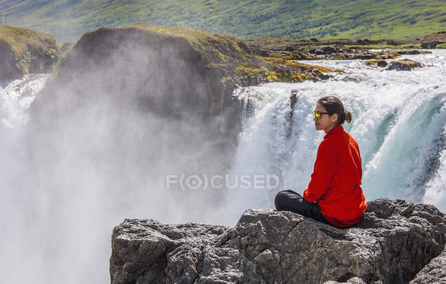 Un hombre está sentado en el borde de la montaña - foto de stock