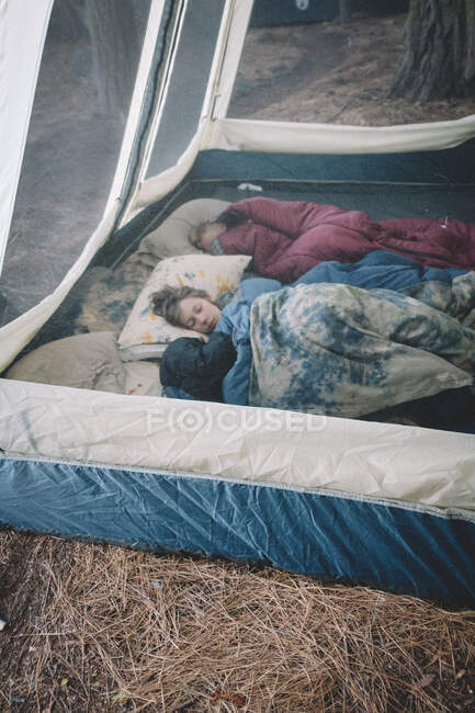 Dos chicos durmiendo y acogedor en la tienda de campaña de lujo - foto de stock