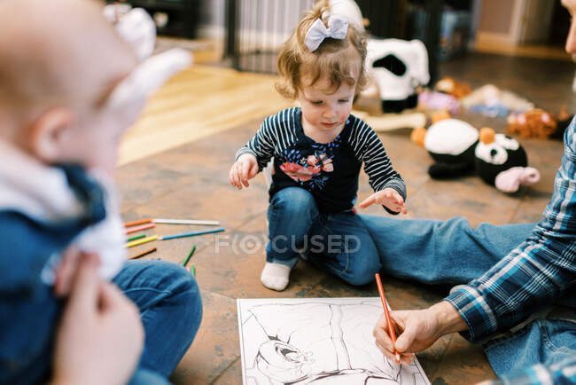 Ein kleines Kleinkind Mädchen Färbung auf dem Boden mit ihren Eltern zusammen — Stockfoto