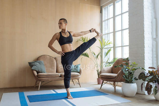 Подходит женщина, занимающаяся йогой баланс упражнения на дому — стоковое фото