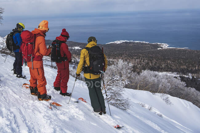 Les gens en vêtements chauds avec des planches à neige donnant sur le paysage pendant les vacances — Photo de stock
