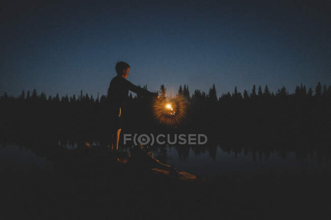 Cara de menino pequeno é iluminado por um sparkler no crepúsculo — Fotografia de Stock
