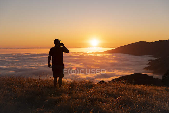 Silhouette d'un homme avec un sac à dos au sommet de la montagne — Photo de stock