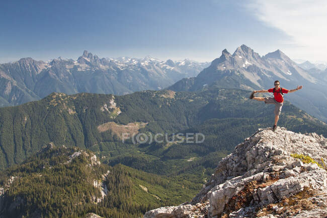 Trail runner balances and stretches on a mountain summit. — Stock Photo