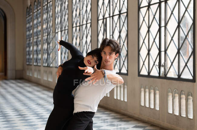Hombre abrazando a la mujer positiva e inclinándose hacia atrás mientras practica danza apasionada - foto de stock