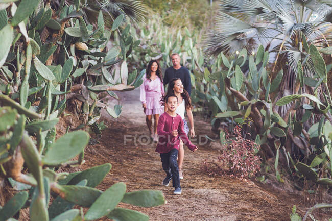 Vierköpfige Familie spaziert glücklich auf Kakteenpfad. — Stockfoto