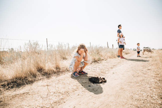 Menina olhando para cocô de cavalo, enquanto em uma caminhada pela natureza — Fotografia de Stock