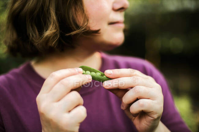 Mulher comendo ervilhas orgânicas do jardim do quintal — Fotografia de Stock