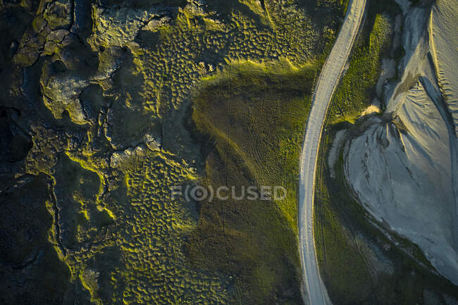 Vista superior del camino de asfalto con curvas que atraviesa un terreno seco y musgoso en el día de verano en la naturaleza - foto de stock
