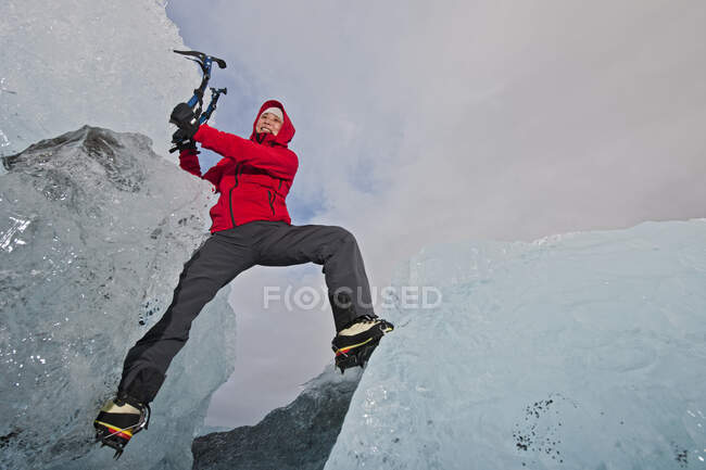 Woman climbing iceberg on the south coast of Iceland using ice pick — Stock Photo