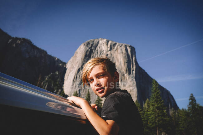 Blonder Junge hängt mit El Cap im Hintergrund aus dem Autofenster — Stockfoto