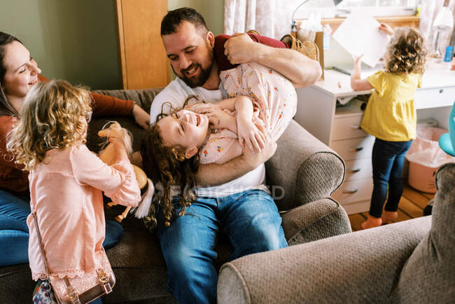 Jovem família feliz de cinco rindo e brincando juntos em casa — Fotografia de Stock
