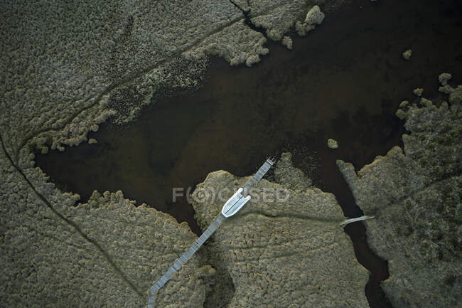 Vista aérea del muelle largo con barco situado cerca del agua en el humedal en la naturaleza - foto de stock