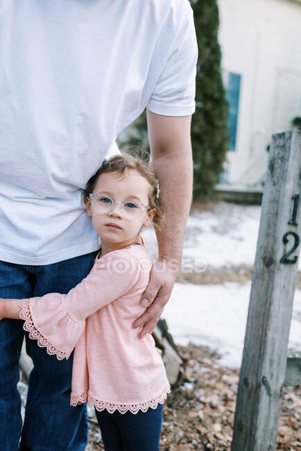 Pequena menina em idade pré-escolar com óculos segurando em seu pai — Fotografia de Stock