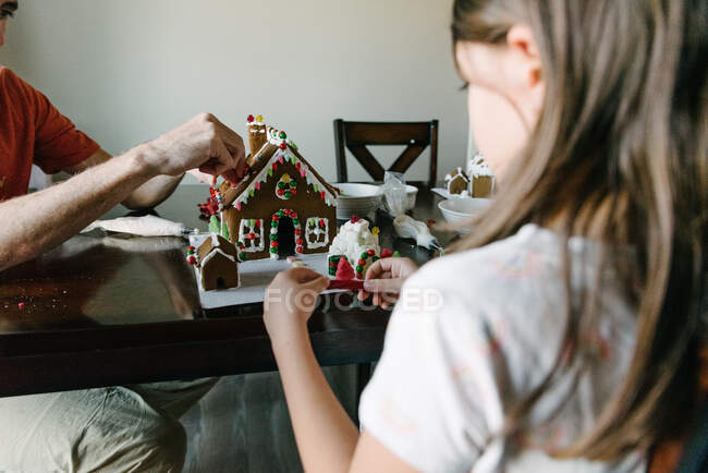 Pai e filha fazer casas de gengibre juntos na mesa da cozinha — Fotografia de Stock
