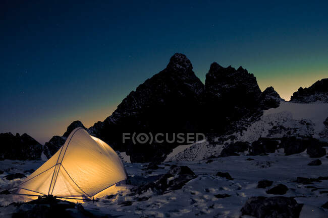 Illuminated tent below Canada mountains under the night sky. — Stock Photo
