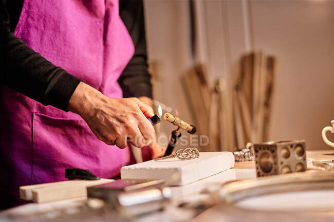 Jeweler craftsman lighting torch at work table — Stock Photo