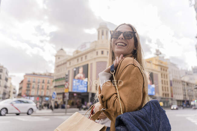 Hermosa mujer sosteniendo bolsas de compras y sonriendo - foto de stock