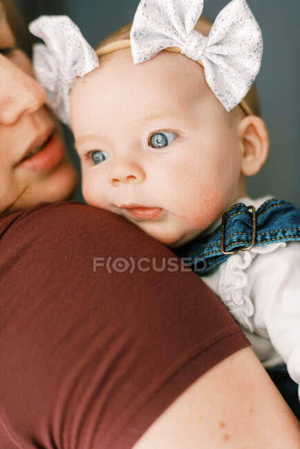 Una bambina tra le braccia di sua madre che guarda con sorpresa — Foto stock
