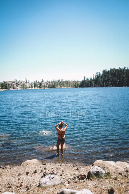 Frau im Bikini frisiert sich vor Sprung in Alpensee die Haare — Stockfoto