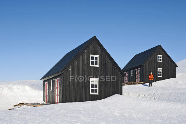Mujer partiendo hacia una caminata desde una casa de esquí en Islandia - foto de stock