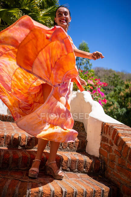 Vertical photo of a woman in a colourful dress flying with the movement — Stock Photo