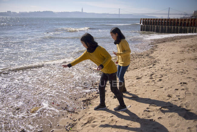 Дві дівчини на березі річки Тежу кидають камінці в річку.. — стокове фото