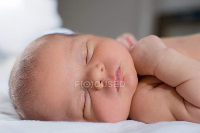 Bebê recém-nascido com bochechas gordinhas e lábios rosa dormindo na cama. — Fotografia de Stock