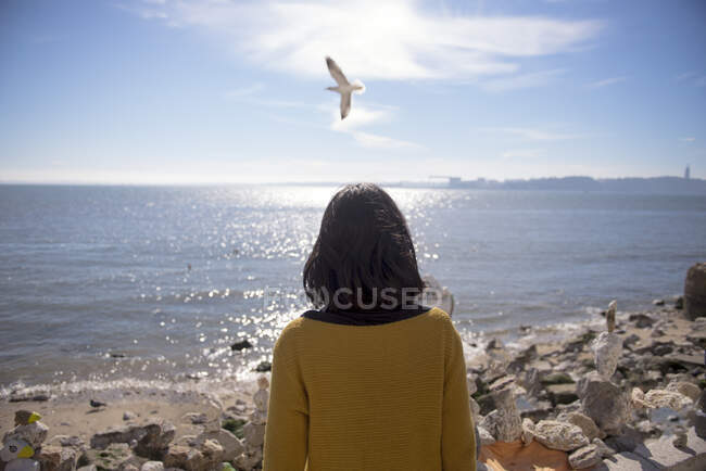 Самотня дівчина на березі річки, стоїть зі спиною — стокове фото