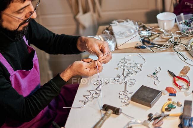Jeweler craftsman working at table with work tools inside workshop — Stock Photo