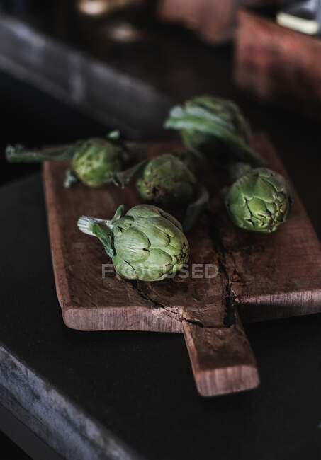 Fresh green artichokes on wooden table — Stock Photo