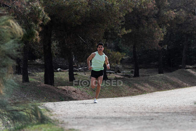 Hombre sudamericano corriendo por un sendero natural en el bosque - foto de stock