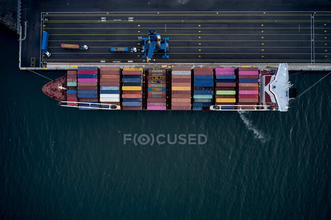 Drone vista superior de contenedores de colores cargados en barcaza amarrado en el muelle del puerto de embarque - foto de stock