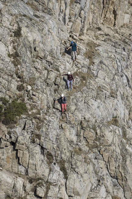 Amigos hombres y mujeres haciendo senderismo en acantilado rocoso - foto de stock