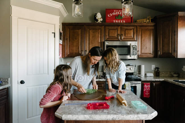 Mother making gingerbread houses with kids daughters at home — Stock Photo